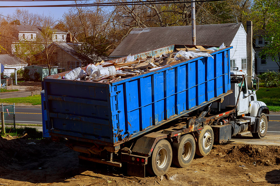 A dumpster is filled with trash in Danbury, Connecticut, and a truck hauls them away.