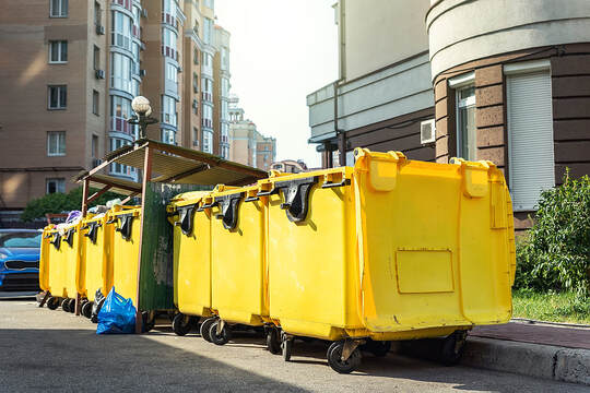 In Danbury, CT, a row of large yellow plastic dumpsters is filled with garbage.