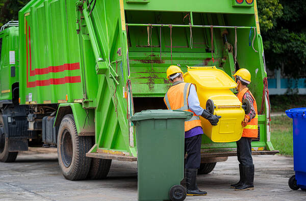 Two men are working on emptying dustbins for trash removal in Danbury, CT.